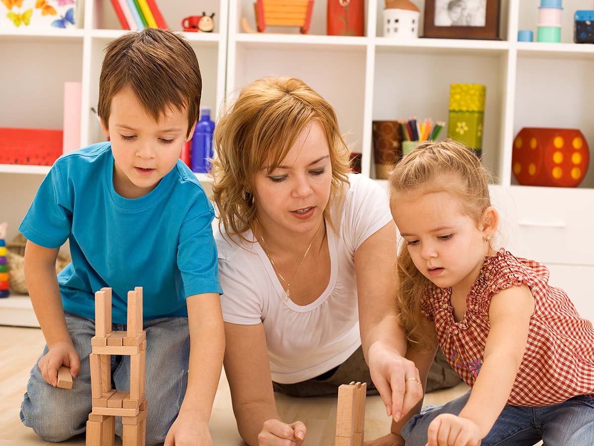 a woman playing with a couple of children