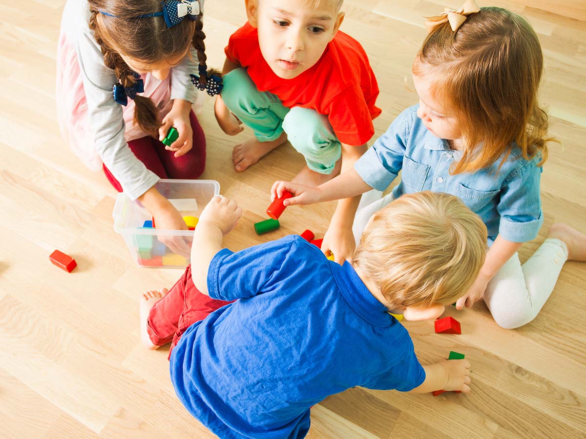children clean up their toys together
