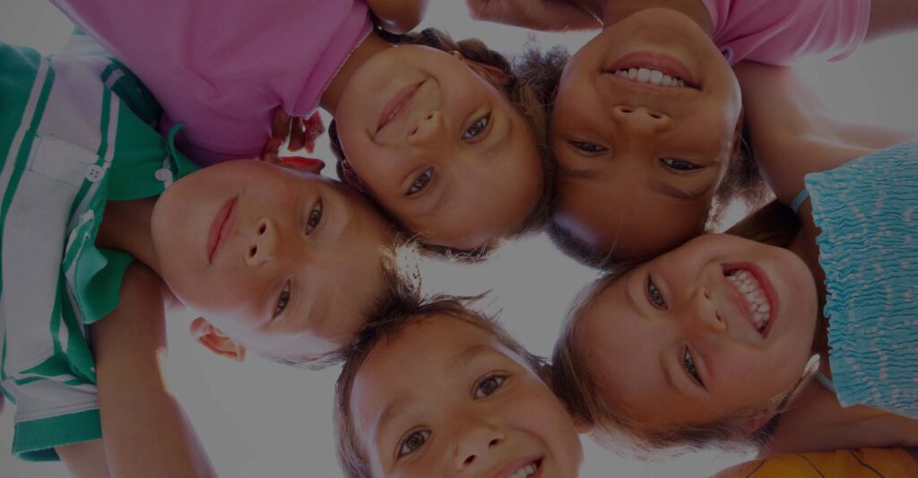 Children huddled up together and smiling down at the camera