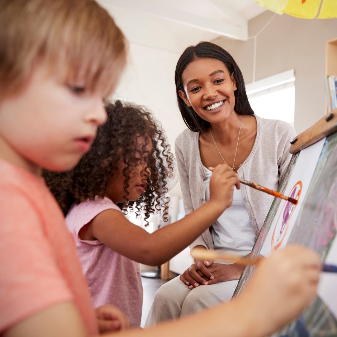 teacher with students creating artwork