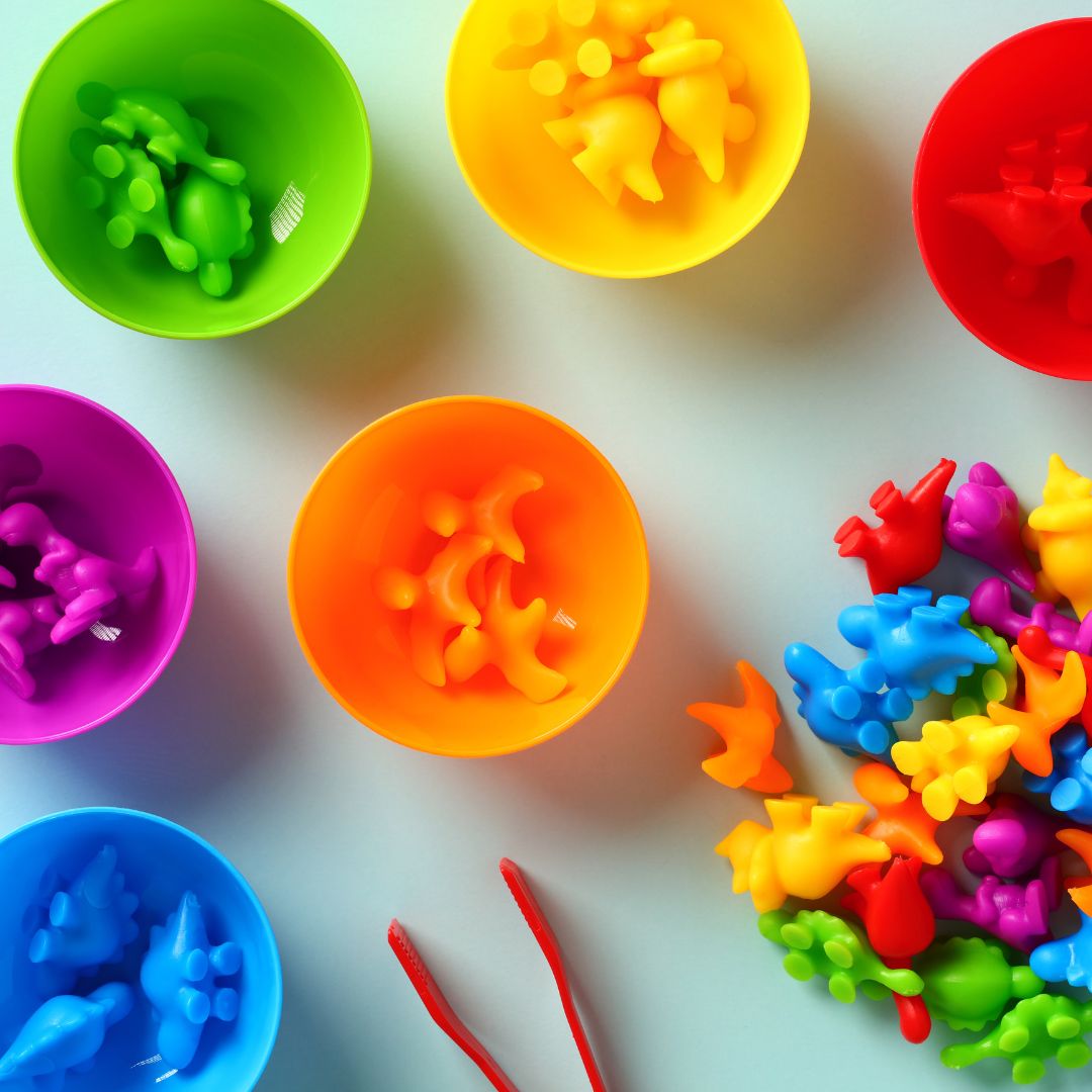 colored dinosaurs sorted into color coordinated bowls