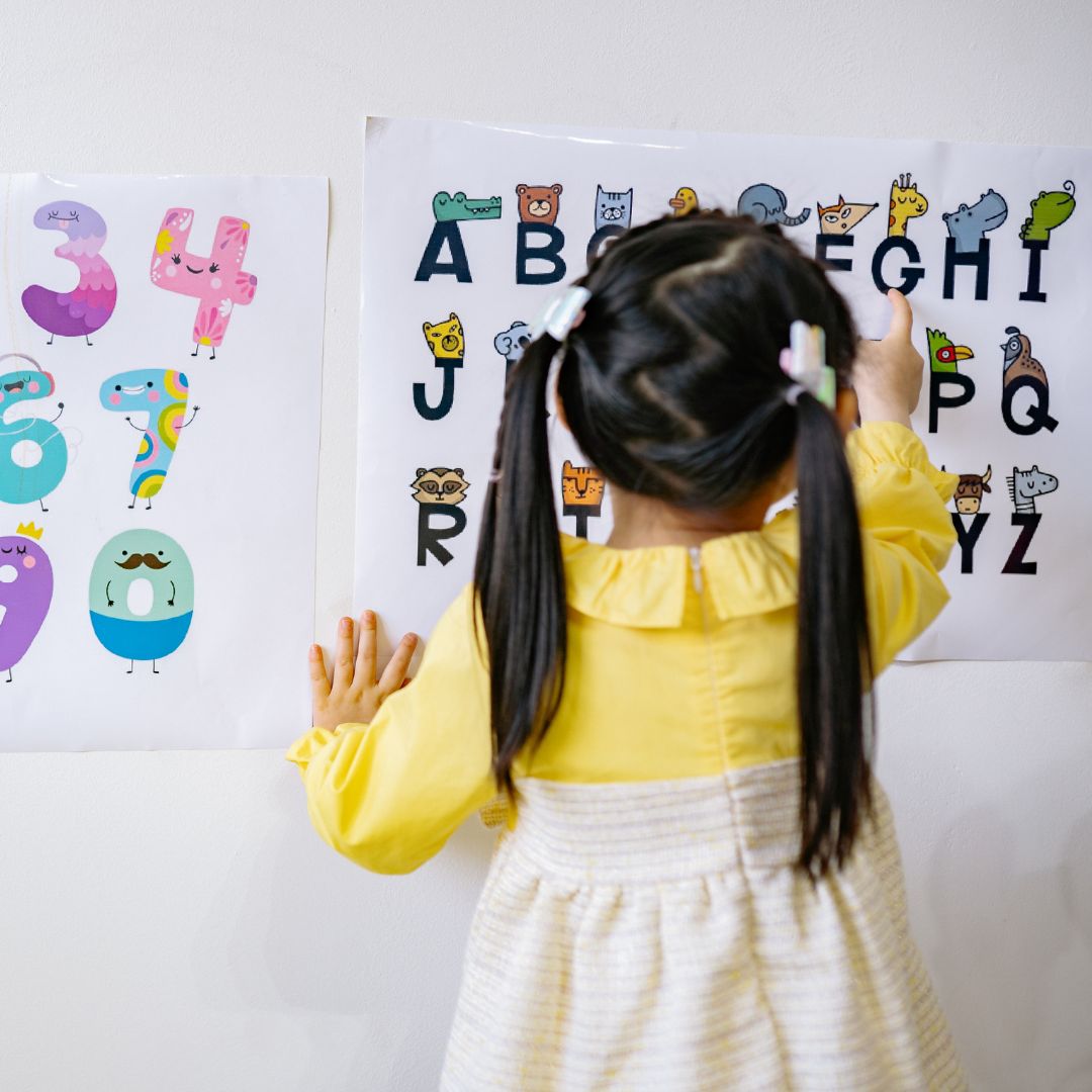 a girl pointing to letters on a paper