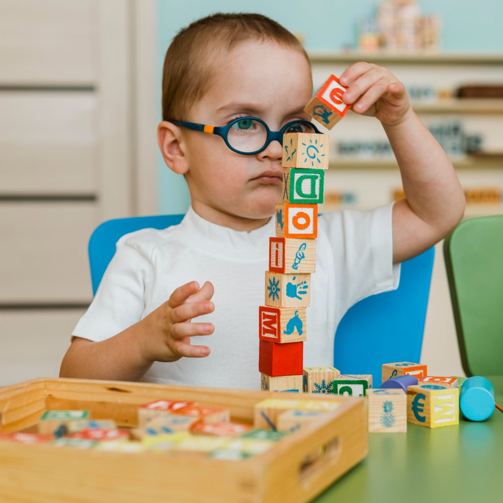 A young boy playing with wooden blocks featuring different letters and corresponding illustrations.