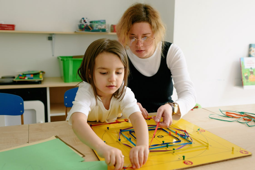 A teacher gently guides a young student working on an activity.