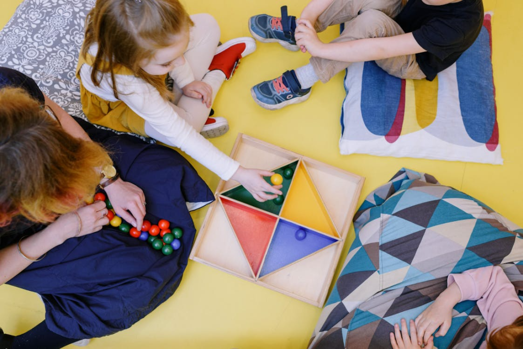 Young children working together to sort colorful items into matching bowls.