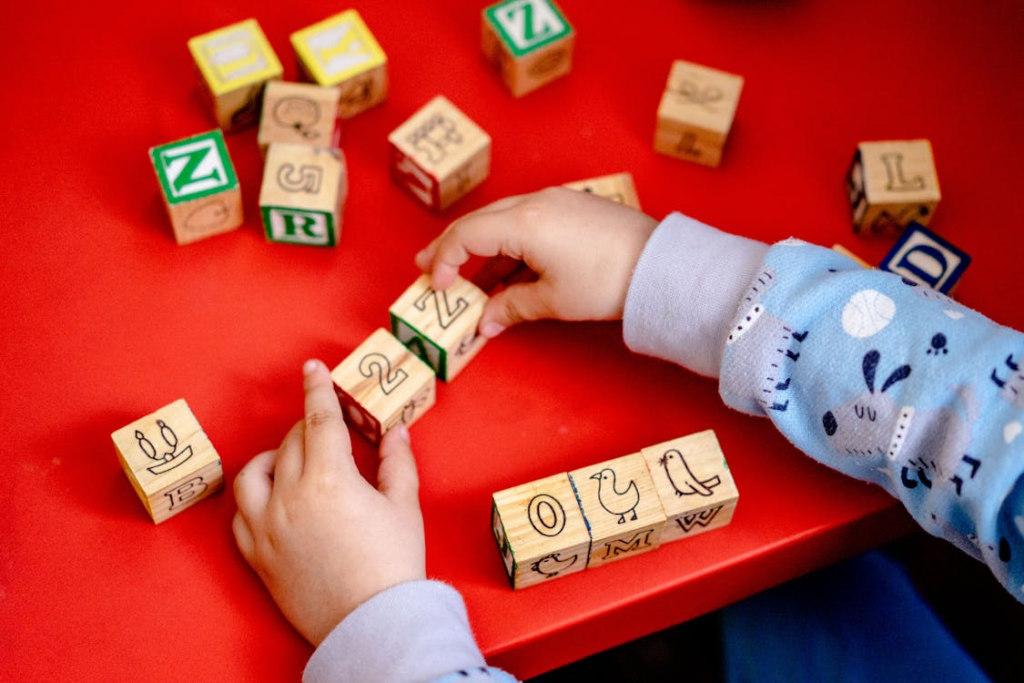 Two hands carefully stacking plain wooden rectangular blocks into a balanced tower.