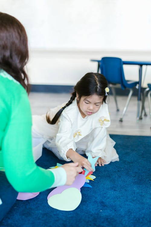 A young girl focusing on arranging colorful cutouts.