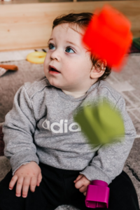 Baby watching colorful building blocks fall during sensory play.
