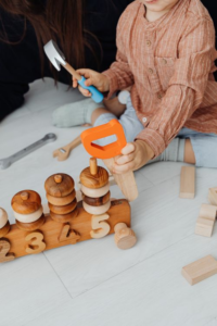 Child exploring wooden tool toys during hands-on learning activity.