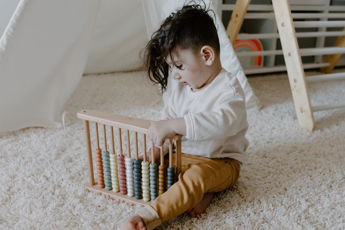 Toddler exploring an abacus during a hands-on Montessori learning activity