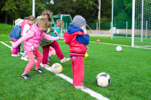 A few toddlers playing soccer on a field