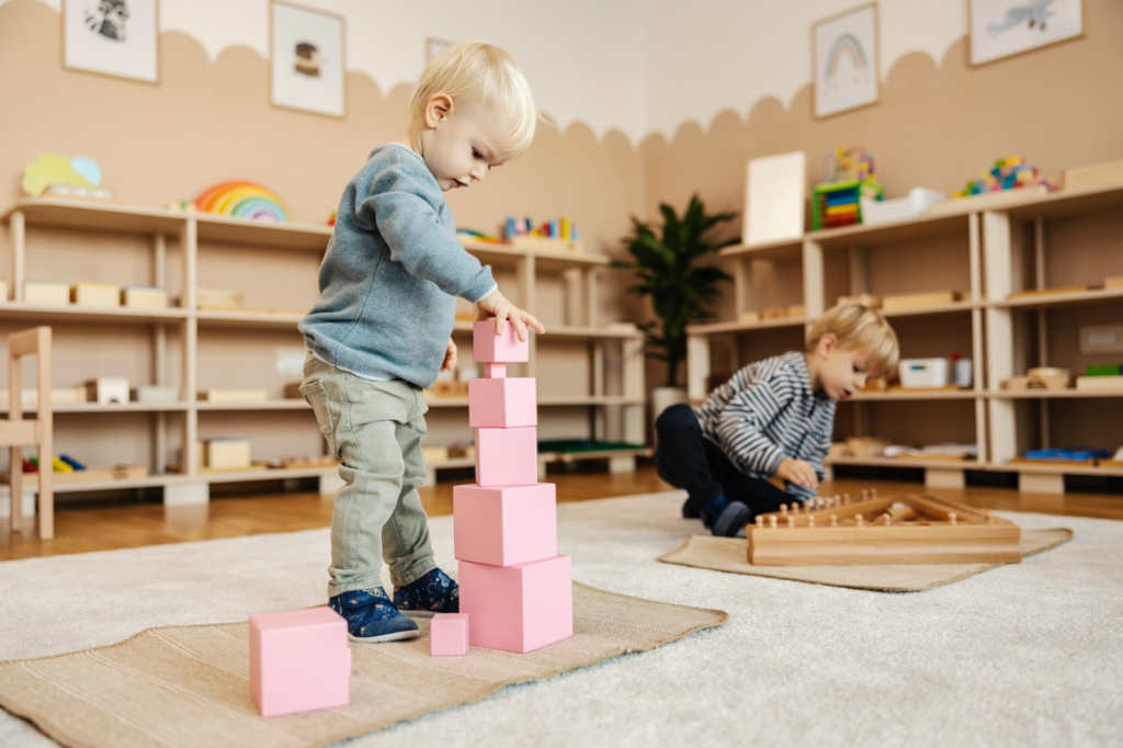 Two children engaged in separate hands-on activities, with one stacking blocks and the other working with learning materials.